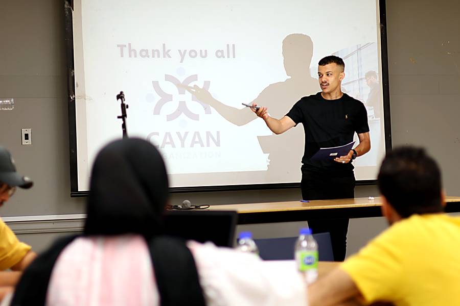 A presenter pointing to the Cayan logo slide