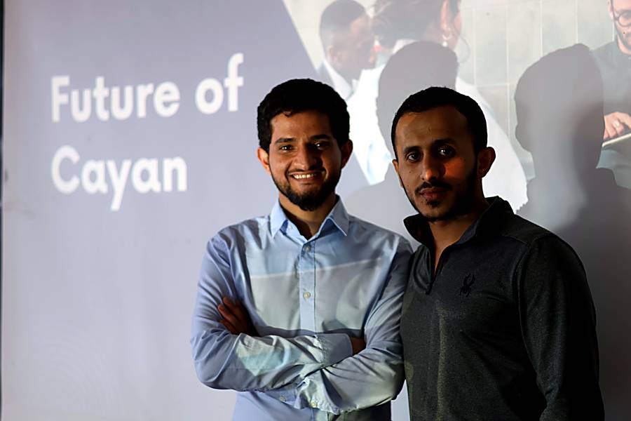 Two people standing in front of the Future of Cayan slide